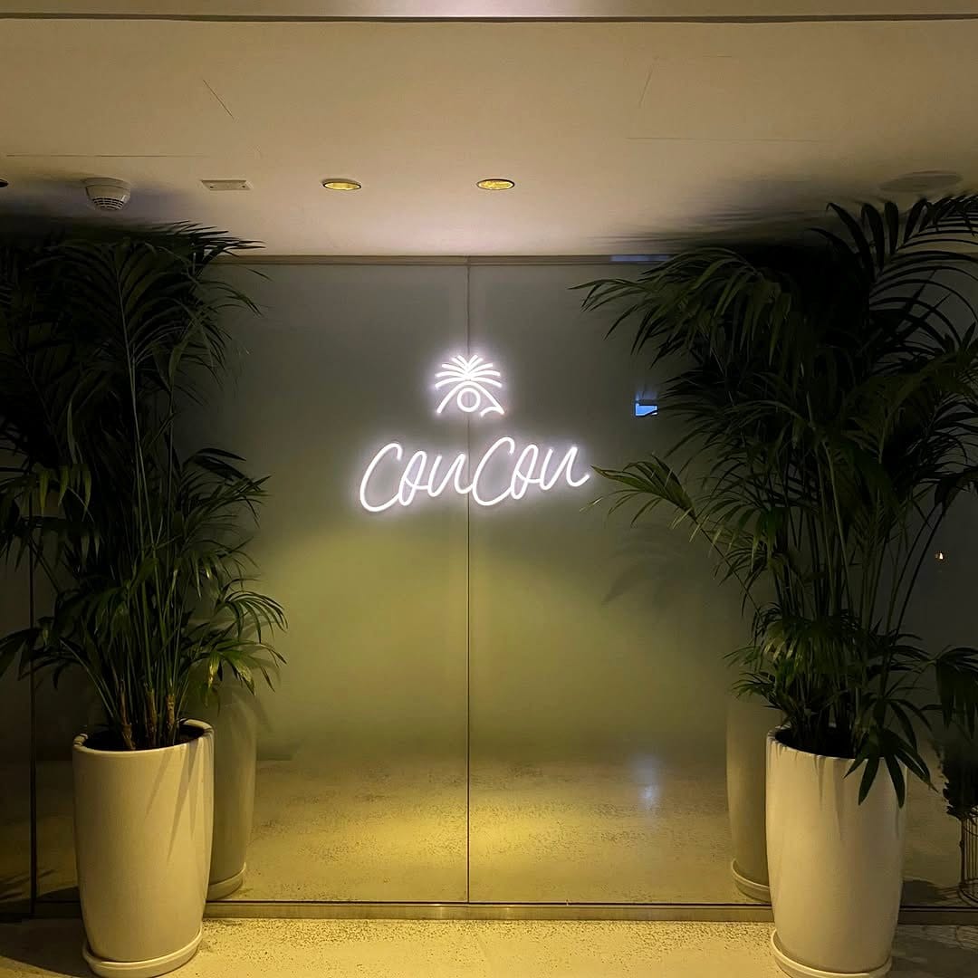 Bright neon palm tree with lush plant wall