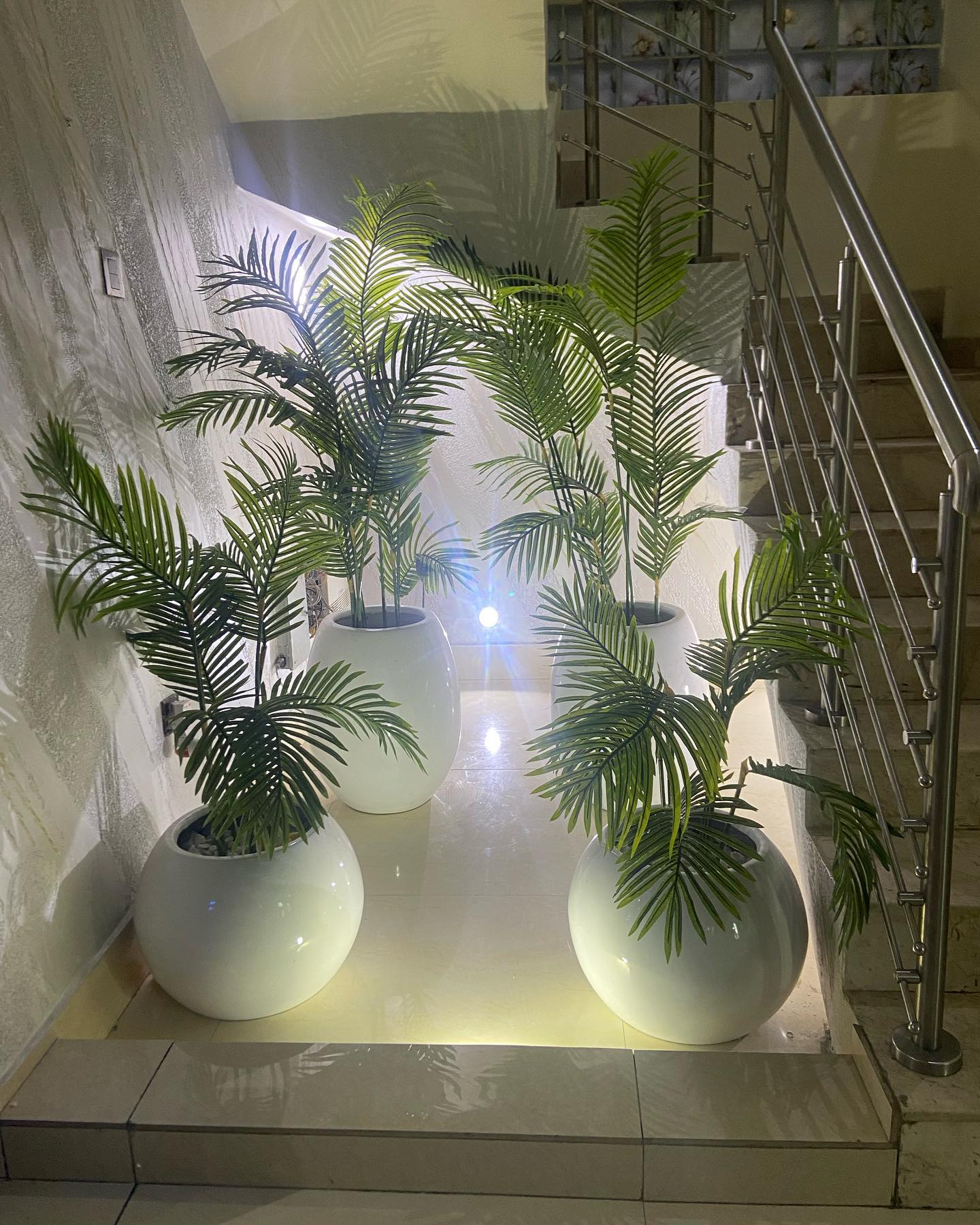tall plant stands with lush plants on staircase landing