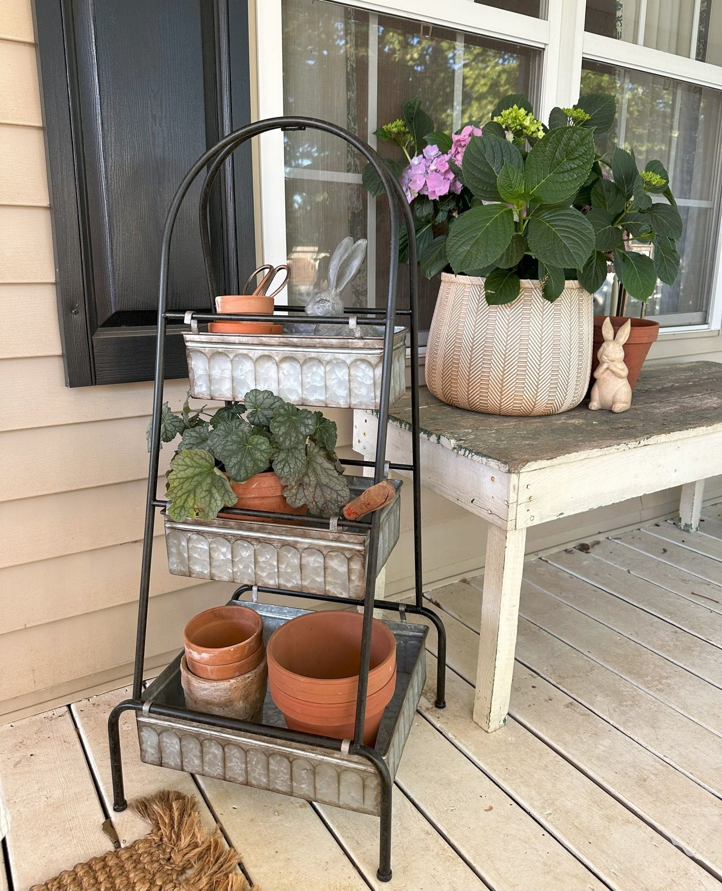 Three-tiered wooden plant stand with diverse plants